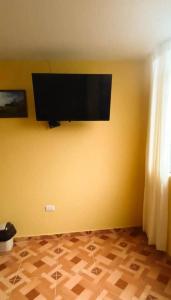 a room with a flat screen tv on a yellow wall at Pretty room in front of the Lima Airport in Lima