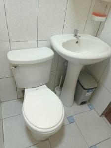 a white bathroom with a toilet and a sink at Pretty room in front of the Lima Airport in Lima