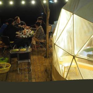 バオロクにあるĐamb'ri Top View Farmstay & Glampingのテントのテーブルに座る人々