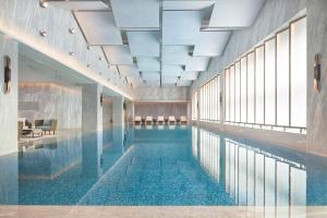 uma piscina com água azul em um prédio em InterContinental Hotels Zhengzhou em Zhengzhou