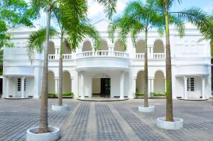 a white building with palm trees in front of it at Bougain Villa in Bentota