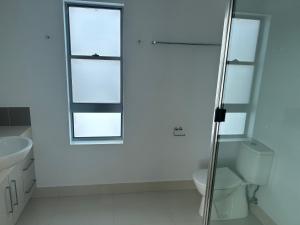 baño blanco con aseo y ventana en Ocean Whisper, en Bargara