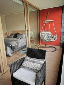 um quarto com uma cama, uma cadeira e um baloiço em Moderno departamento cercano al centro de Pucón em Pucón