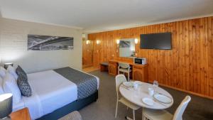 a hotel room with a bed and a table with chairs at Blue Diamond Motor Inn in Dubbo