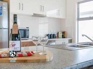 Una botella de vino y dos vasos en una barra de cocina en Ocean & Island Views for Miles – 4BR + 2.5 Baths, en Encounter Bay