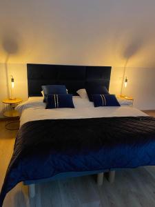 een groot bed met blauwe en witte lakens en kussens bij Espace privé - Gîte & Spa 