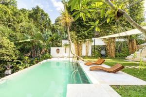 a swimming pool with two lounge chairs next to a house at PROMO! Luxury Villa Escape in Ubud 2 BR in Ubud