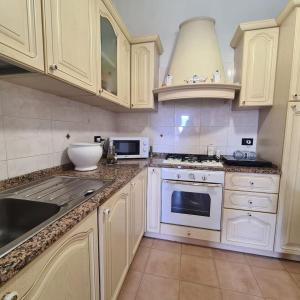 una cucina bianca con mobili bianchi e un lavello di Casa Orchidea a La Spezia a La Spezia Altre 2 foto