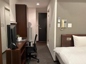 東京にあるサイプレスイン東京のベッド、デスク、コンピュータが備わるホテルルームです。