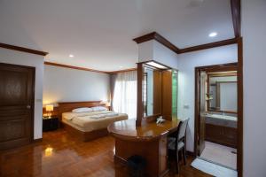 曼谷的住宿－Baan Sawasdee Residence，一间卧室配有一张床、一张桌子和一张桌子