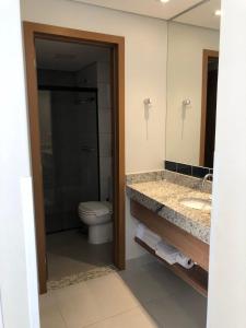 a bathroom with a toilet and a sink and a mirror at Praias do Lago Eco Resort in Caldas Novas