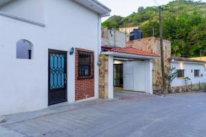 a white building with a black door on a street at Casa Nieto in Teotitlán del Camino
