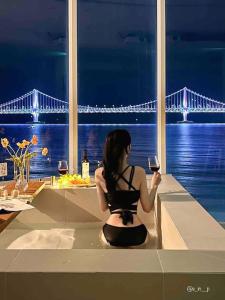 a woman sitting on a counter looking out at a bridge at Stay moment in Busan +142 photos
