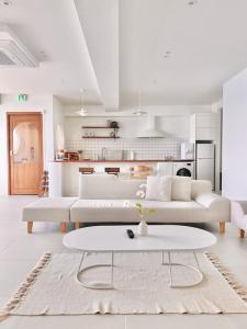 ein weißes Wohnzimmer mit einem weißen Sofa und einem Tisch in der Unterkunft Stay moment in Busan
