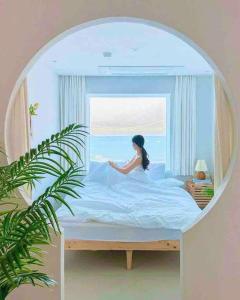 una donna seduta su un letto in una stanza con finestra di Stay moment a Busan