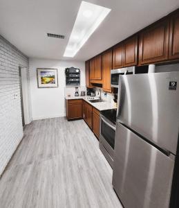 una cocina con nevera de acero inoxidable y armarios de madera en Cozy 3 Bedroom house near Airport/Raymond Stadium/Downtown., en Tampa