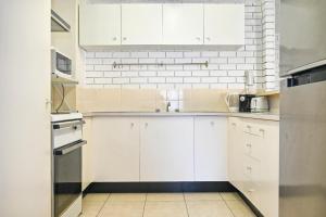 a kitchen with white cabinets and a white brick wall at Location is Everything - Shops, Beaches, Views ZG3 in Caloundra