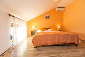 ein Schlafzimmer mit einem Bett mit einer orangefarbenen Wand in der Unterkunft Apartment Vesna - 100m from sea in Luka