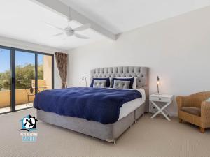 a bedroom with a large bed with a blue blanket at Absolute Water Frontage w/ Jetty + Boat Ramp in Hindmarsh Island