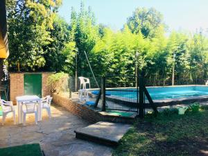 un patio trasero con piscina, mesa y sillas en Casa Quinta Tigre Benavidez en Benavídez