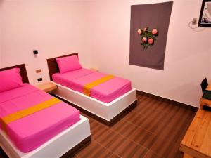 two beds in a room with pink and yellow sheets at BBoutique Hotel in Lapu Lapu City