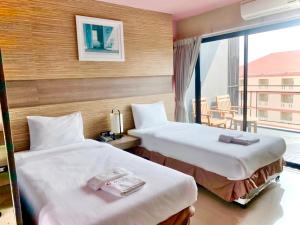 two beds in a hotel room with a balcony at Samkwan Village in Bangsaen