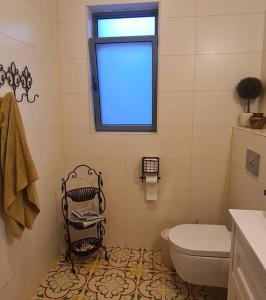 La salle de bains est pourvue de toilettes blanches et d'une fenêtre. dans l'établissement בית לוי, à Dishon