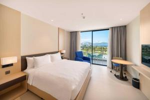 a hotel room with a bed and a desk and a window at Arena in Dien Khanh