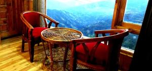 a table and chairs in a room with a window at Humble Holiday Home Kufri S H I M L A with Lawn and Amazing View in Kūfrī