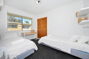 two beds in a room with a desk and a window at Bungalow on the Beach 4 B/R, 8 Guests, Aircon ZG2 in Buddina