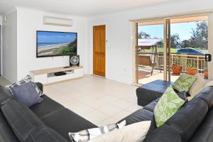 a living room with a couch and a flat screen tv at Bungalow on the Beach 4 B/R, 8 Guests, Aircon ZG2 in Buddina