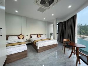 una camera d'albergo con due letti e un tavolo di Snu Motel - Cao Bằng a Cao Bằng