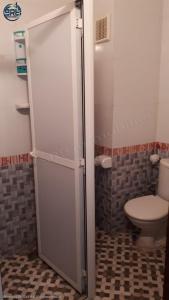 La salle de bains est pourvue de toilettes et d'une porte de douche en verre. dans l'établissement salamappart, à Agadir