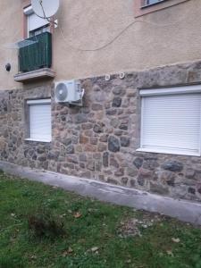 een stenen muur met twee ramen en een luidspreker op een gebouw bij Jószerencsét apartman in Komló