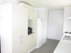 eine Küche mit weißen Schränken und einem Kühlschrank in der Unterkunft The Mitch in Wairoa