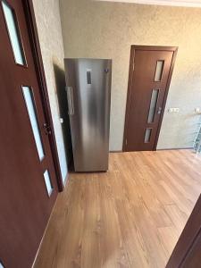 a stainless steel refrigerator in a room with a wooden floor at Комнаты у Айрин in Vanadzor