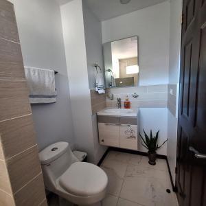a white bathroom with a toilet and a sink at Casa Victoria Hostel in San Isidro