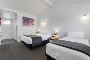 アデレードにあるEcono Lodge East Adelaideのベッド2台と廊下が備わるホテルルームです。