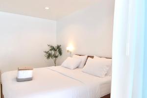 a white bedroom with a white bed with a laptop on it at Beachfront Pool Access Apartment FREE Disney Plus in Bangsaen +18 photos