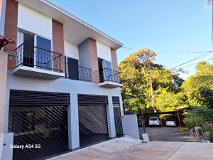 um edifício branco com portas de garagem pretas e um parque de estacionamento em Casa Victoria Hostel em San Isidro