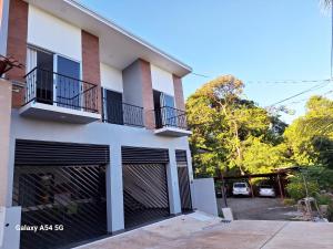 un edificio blanco con puertas de garaje negras y aparcamiento en Casa Victoria Hostel en San Isidro