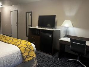 a hotel room with a bed and a desk and a television at Baymont by Wyndham Port Arthur - Groves Area in Port Arthur