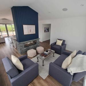 uma sala de estar com dois sofás azuis e uma lareira em Brand new holiday home in Snells Beach em Snells Beach