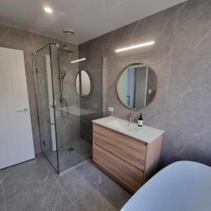 uma casa de banho com um chuveiro, um lavatório e um espelho. em Brand new holiday home in Snells Beach em Snells Beach