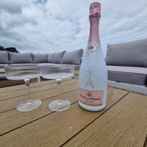 a bottle of champagne and two glasses on a deck at Brand new holiday home in Snells Beach in Snells Beach