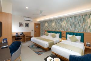 a hotel room with two beds and a desk at Cozzet Victoria Hotel in Bhubaneshwar +65 photos