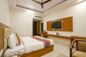 勒克瑙的住宿－FabHotel Aman Sara，一间卧室配有一张床、一张书桌和一台电视。