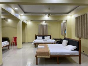 a bedroom with two beds and a red chair at Wayfare SP Resort in Panvel