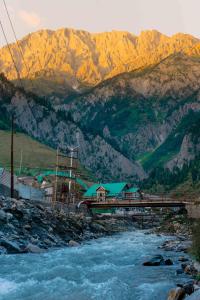 a bridge over a river with mountains in the background at Mitra Hostel Sonamarg in Sonāmarg