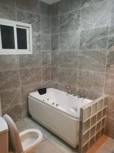 a bathroom with a white tub and a toilet at Appartement coup de cœur in Pointe-Noire